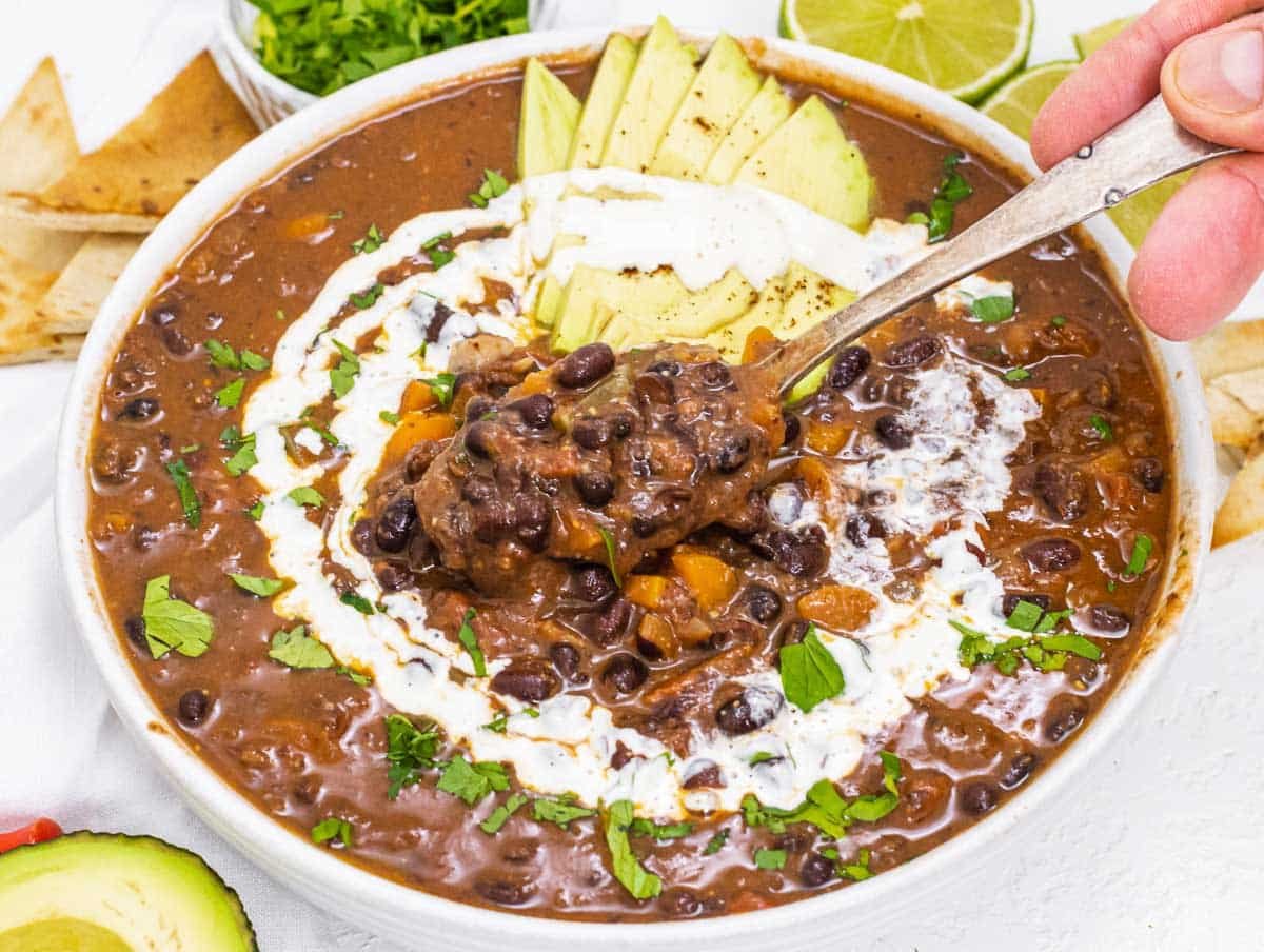 Black bean soup with silver spoon and hand