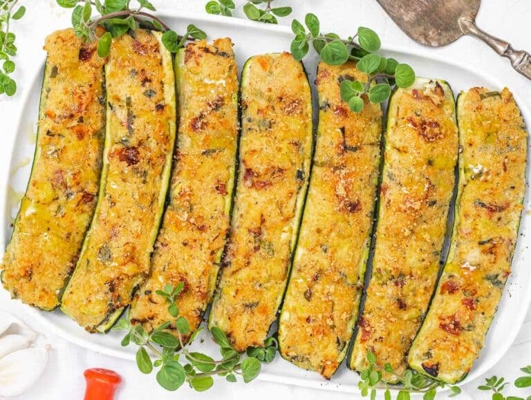 stuffed zucchini on a platter with herbs