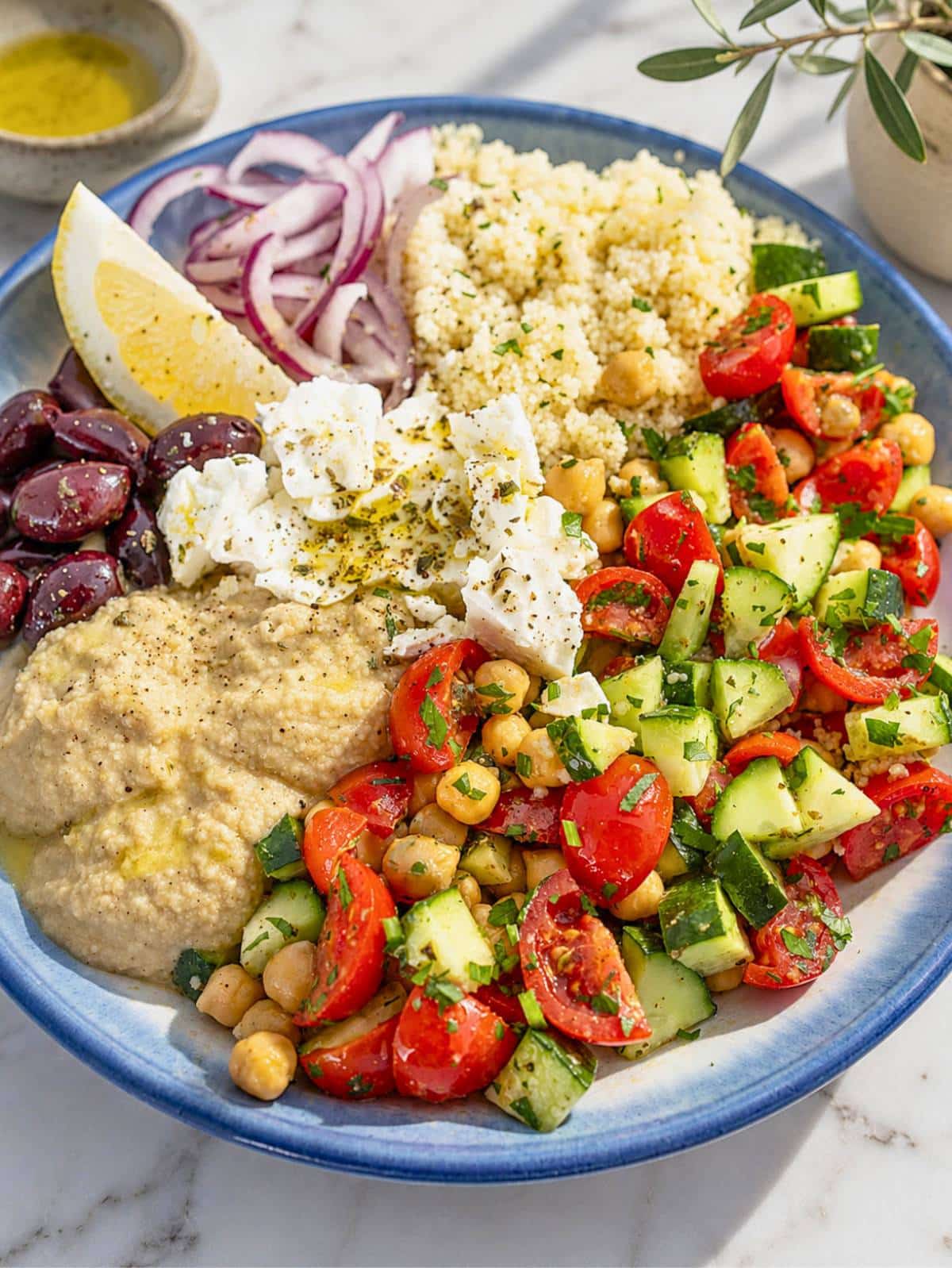Close-up of creamy hummus, marinated chickpeas, feta, cucumber, and juicy tomatoes.
