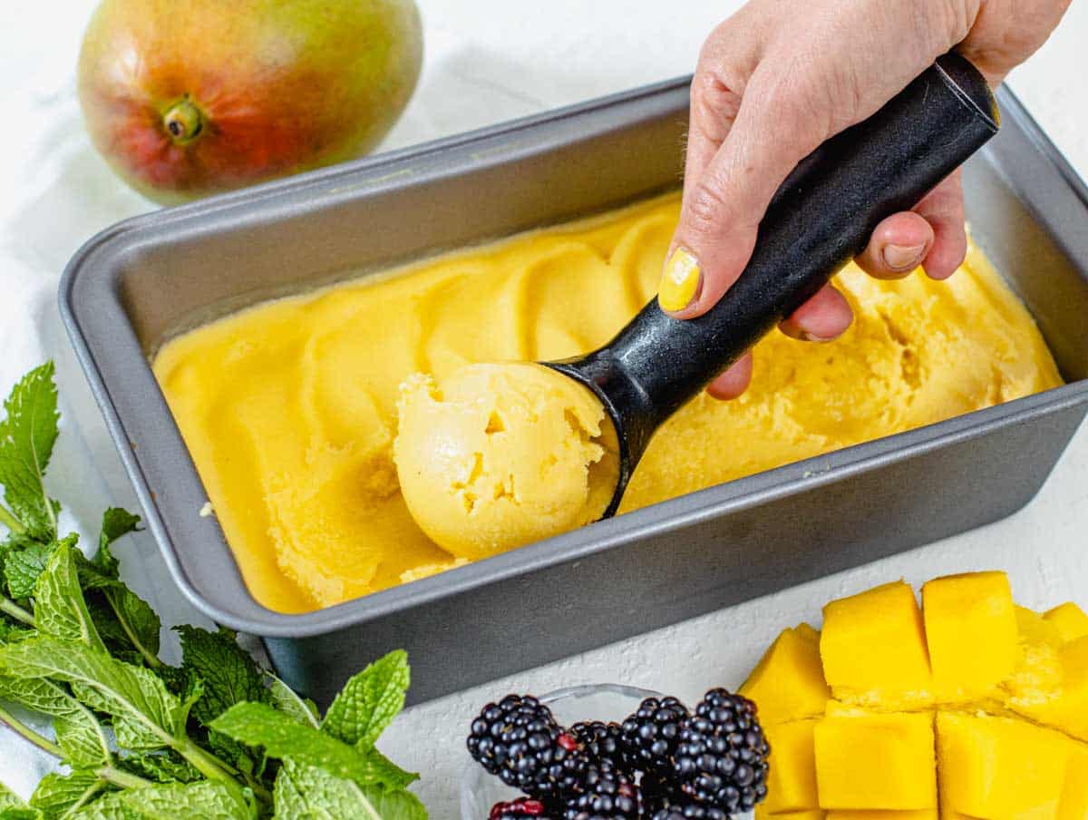 Mango sorbet scoop and hand