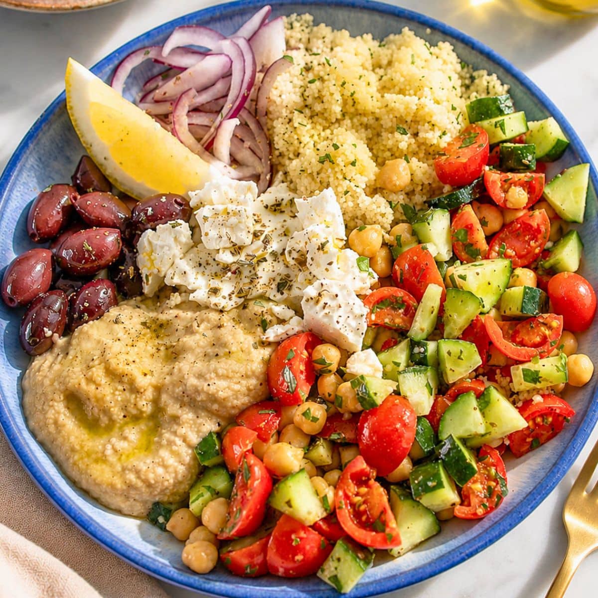 Mediterranean Bowl with hummus, marinated chickpeas, feta, olives, and fresh lemon wedges.