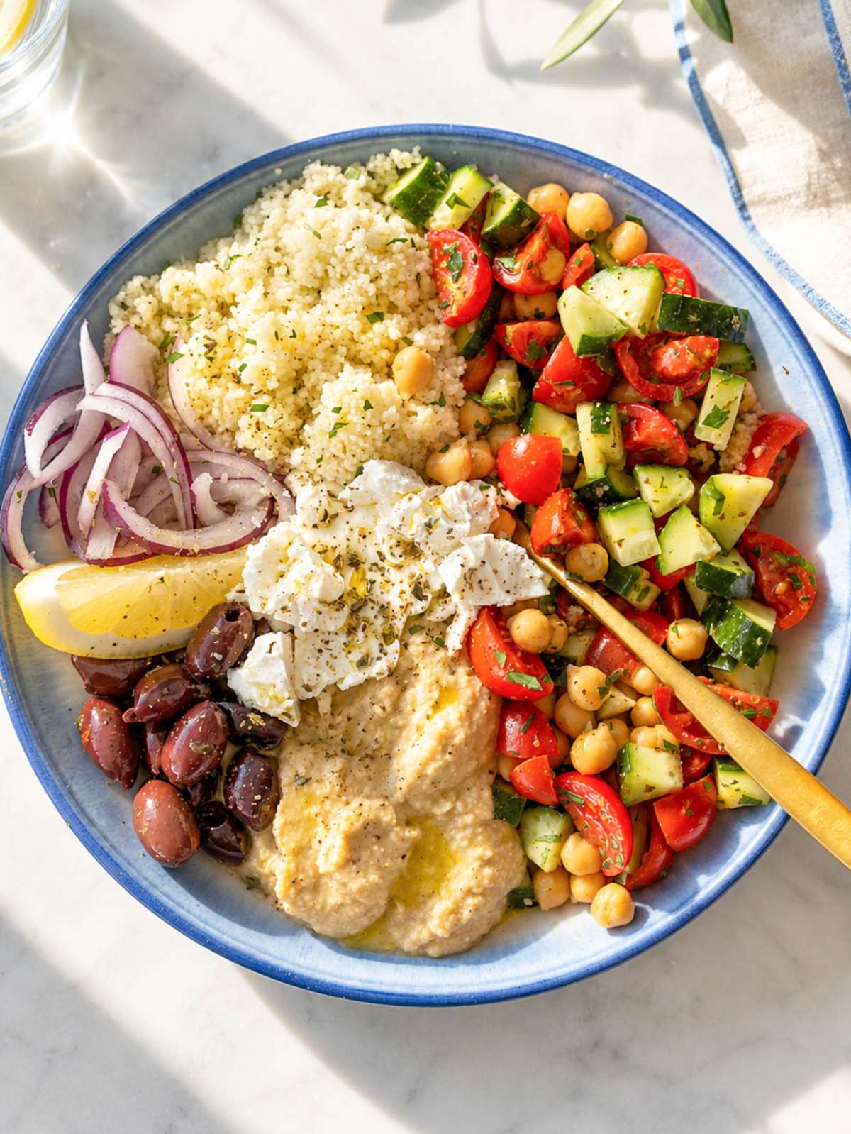 Mediterranean Bowl with marinated chickpeas, hummus, feta, vegetables, and olives.