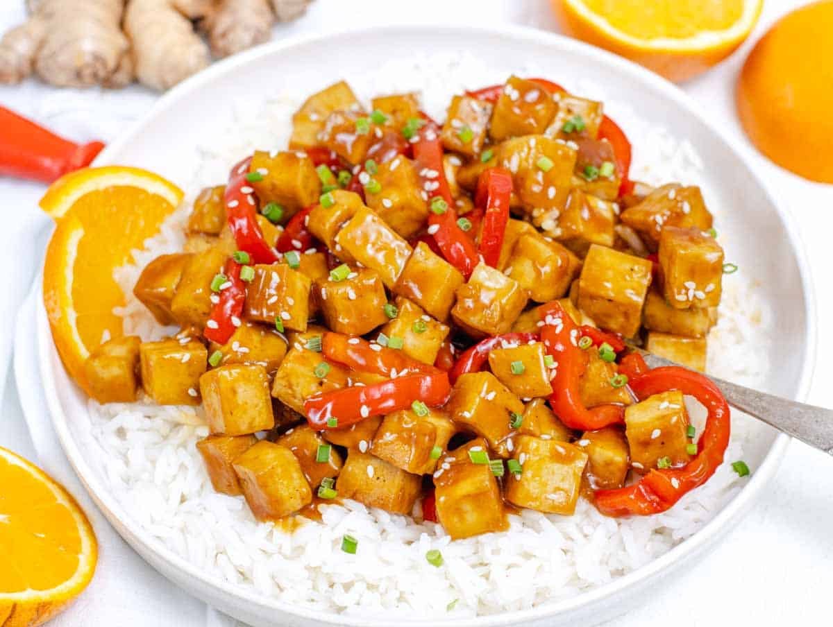 Orange Tofu on a plate with rice and a spoon
