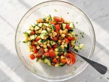 Step 2 Tossing marinated chickpeas with cucumber, tomatoes, and chopped parsley until combined.