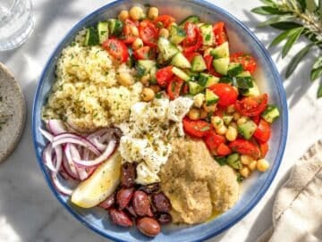 Step 3 Assembling Mediterranean Bowl with hummus, feta, olives, onion, couscous, and lemon wedges.