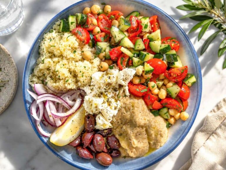 Step 3 Assembling Mediterranean Bowl with hummus, feta, olives, onion, couscous, and lemon wedges.