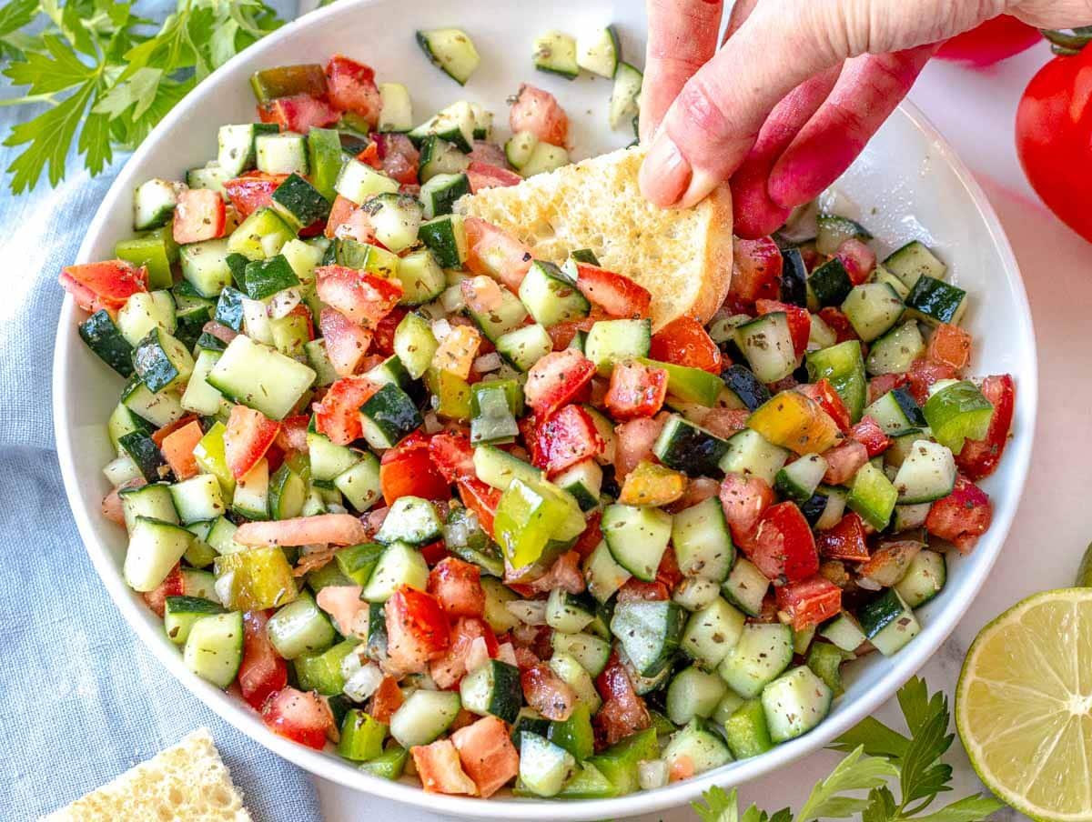 Shirazi salad with bell pepper and hand holding a pita bread