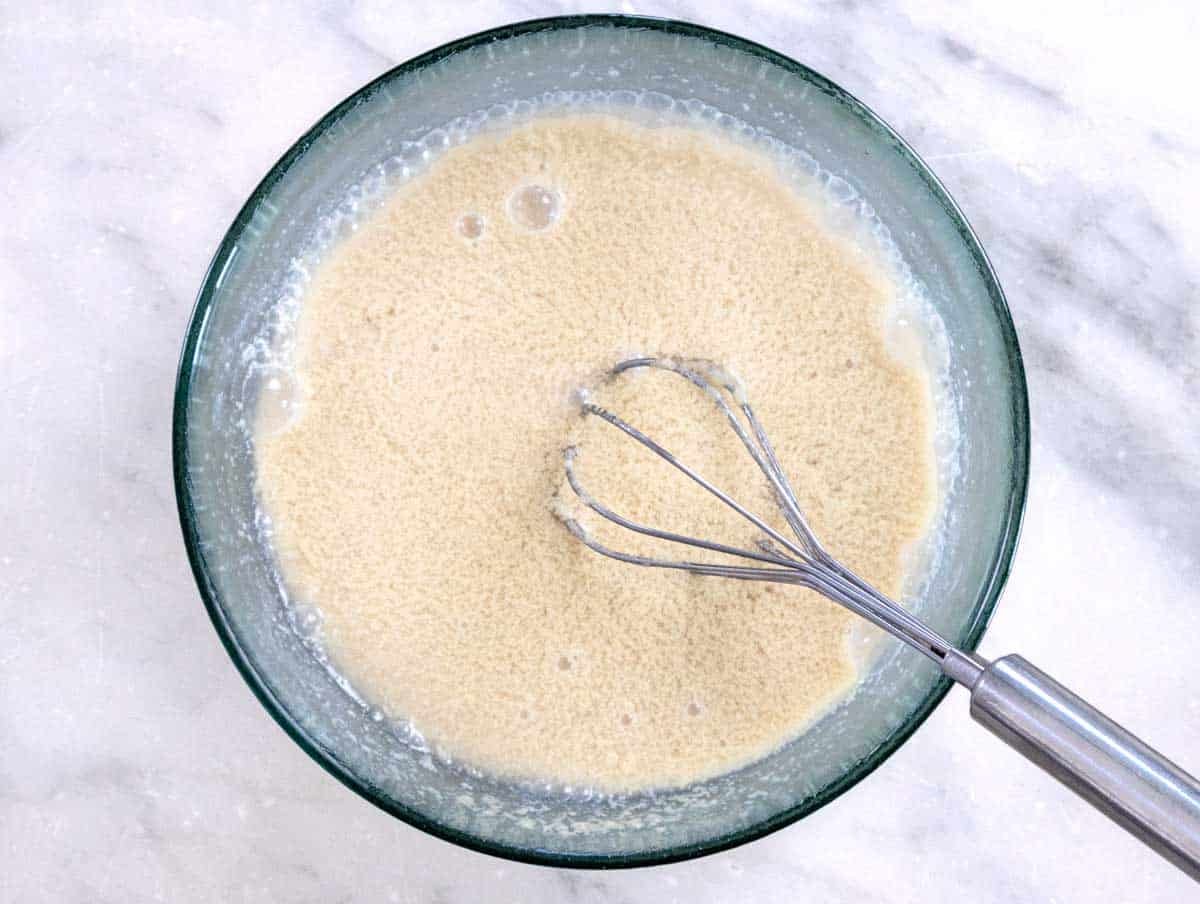 whisk in a glass bowl with ingredients for tahini sauce