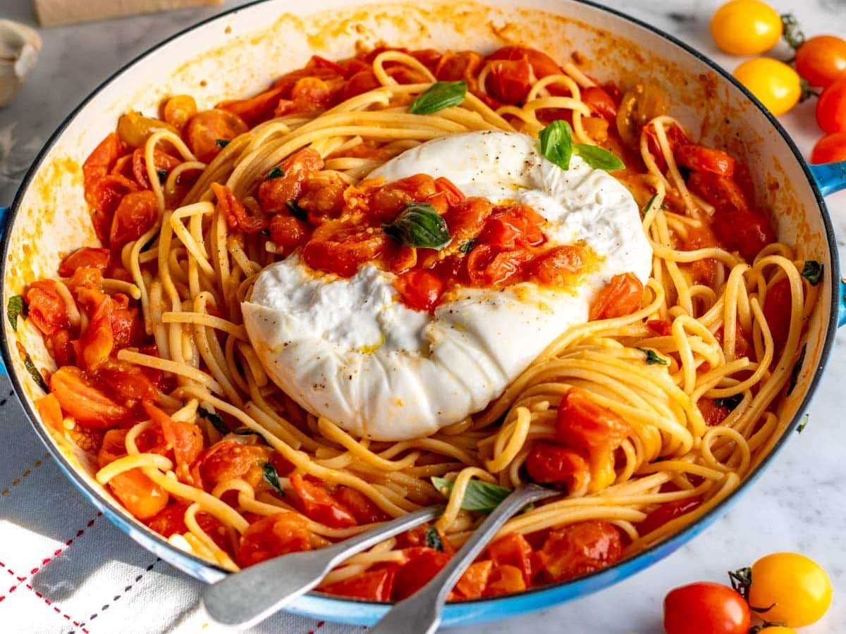 cherry tomato pasta in a blue skillet served with burrata cheese.