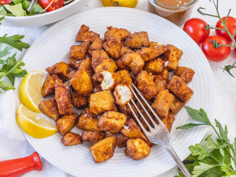 Air fryer tofu on a plate with lemon wedges