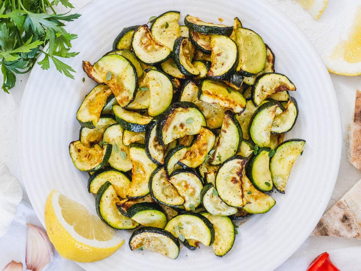 Air fryer zucchini on a plate with lemon wedge