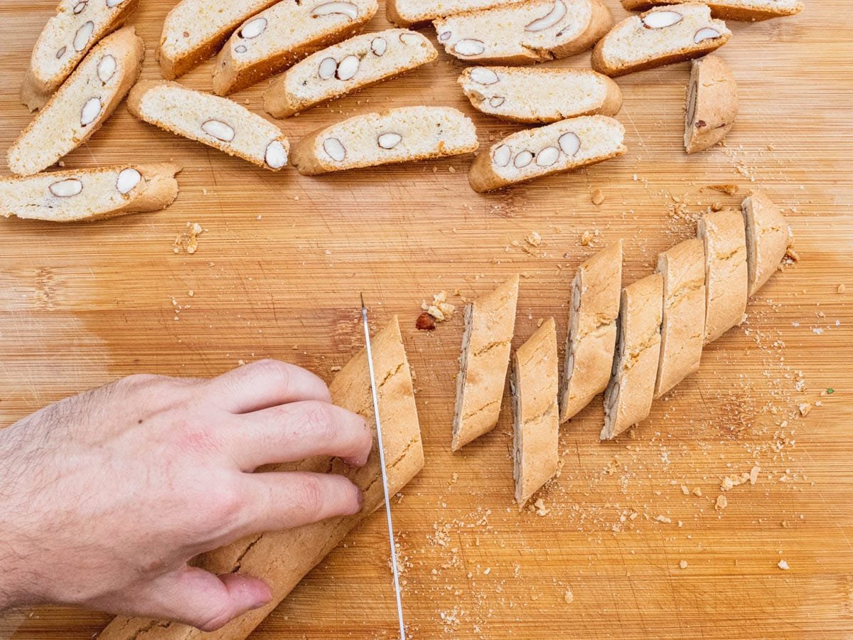 hands and serrated knife cutting biscotti