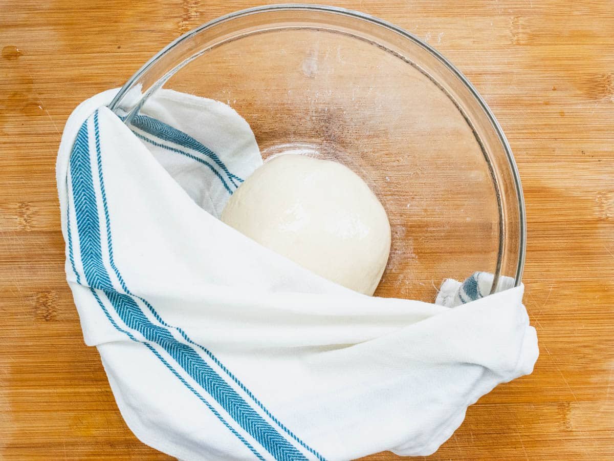 Flatbread pizza dough in a bowl with a cloth