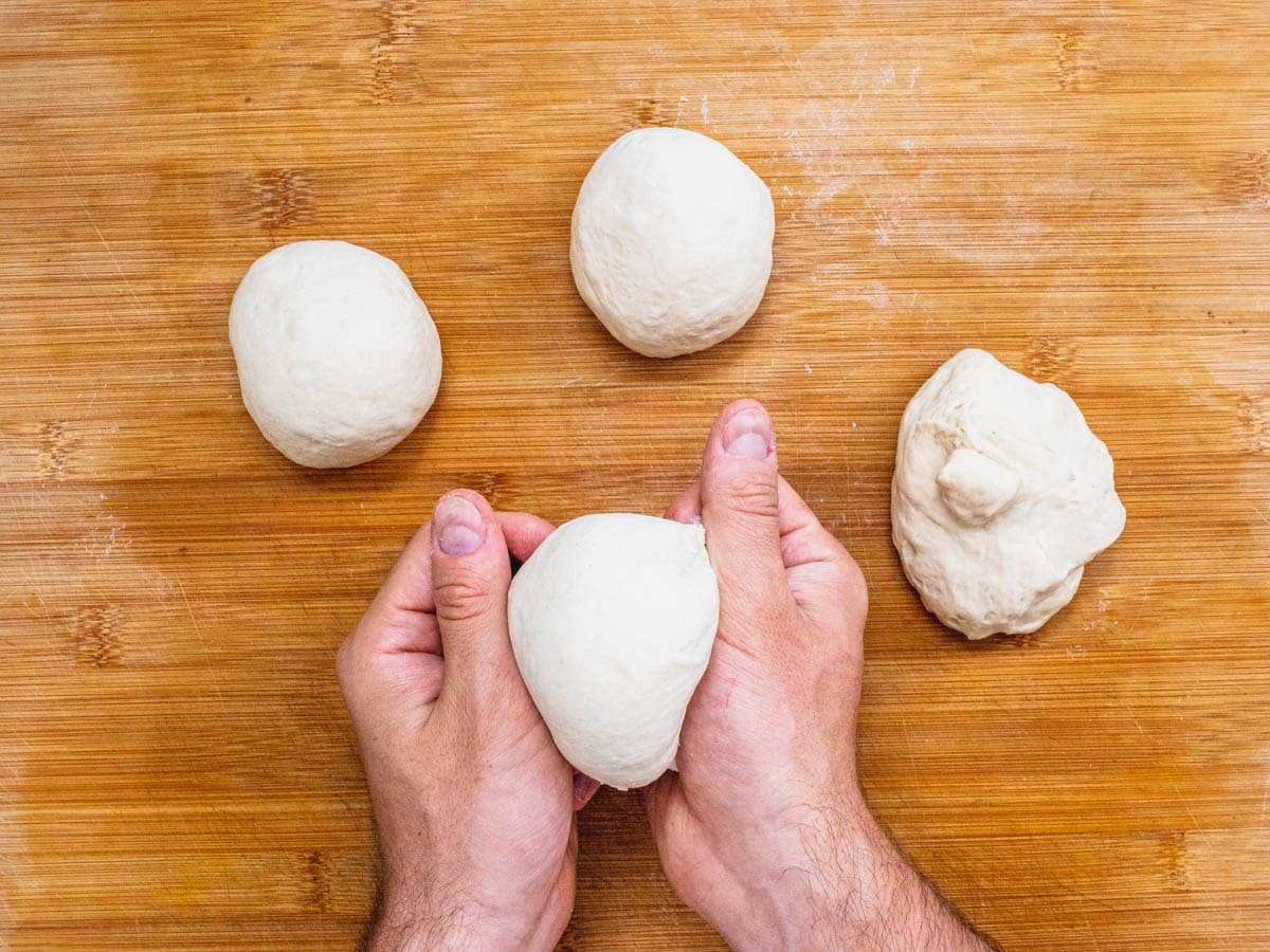 Flatbread pizza dough in 4 balls and hands