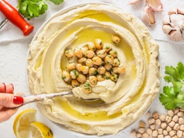 Hummus with a hand and a spoon