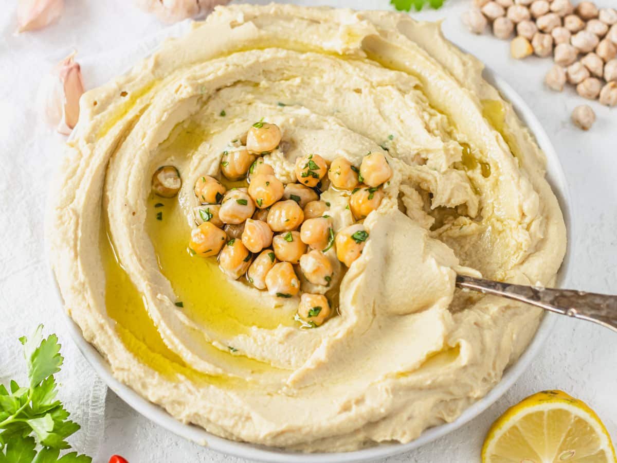 Hummus on a plate with chickpeas in the middle and lemon on the side
