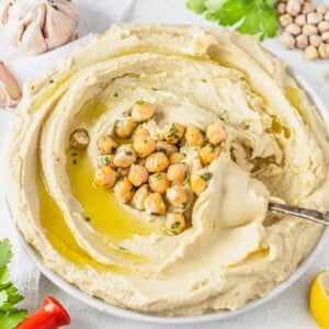 Hummus spread on a plate with chickpeas and parsley in the center