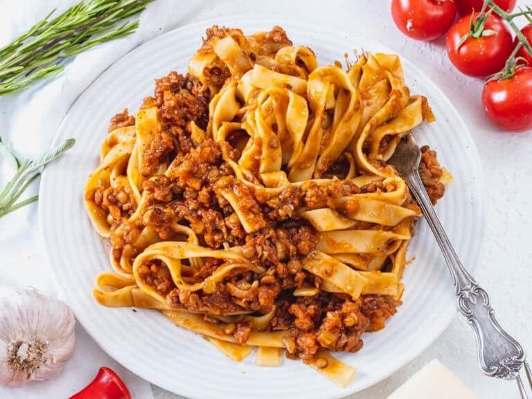 Lentil Bolognese on a white plate with a fork