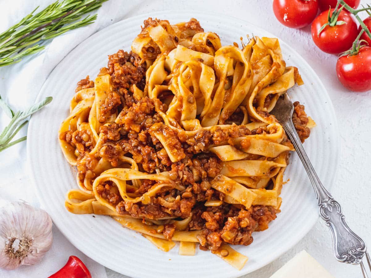 Lentil Bolognese on a white plate with a fork