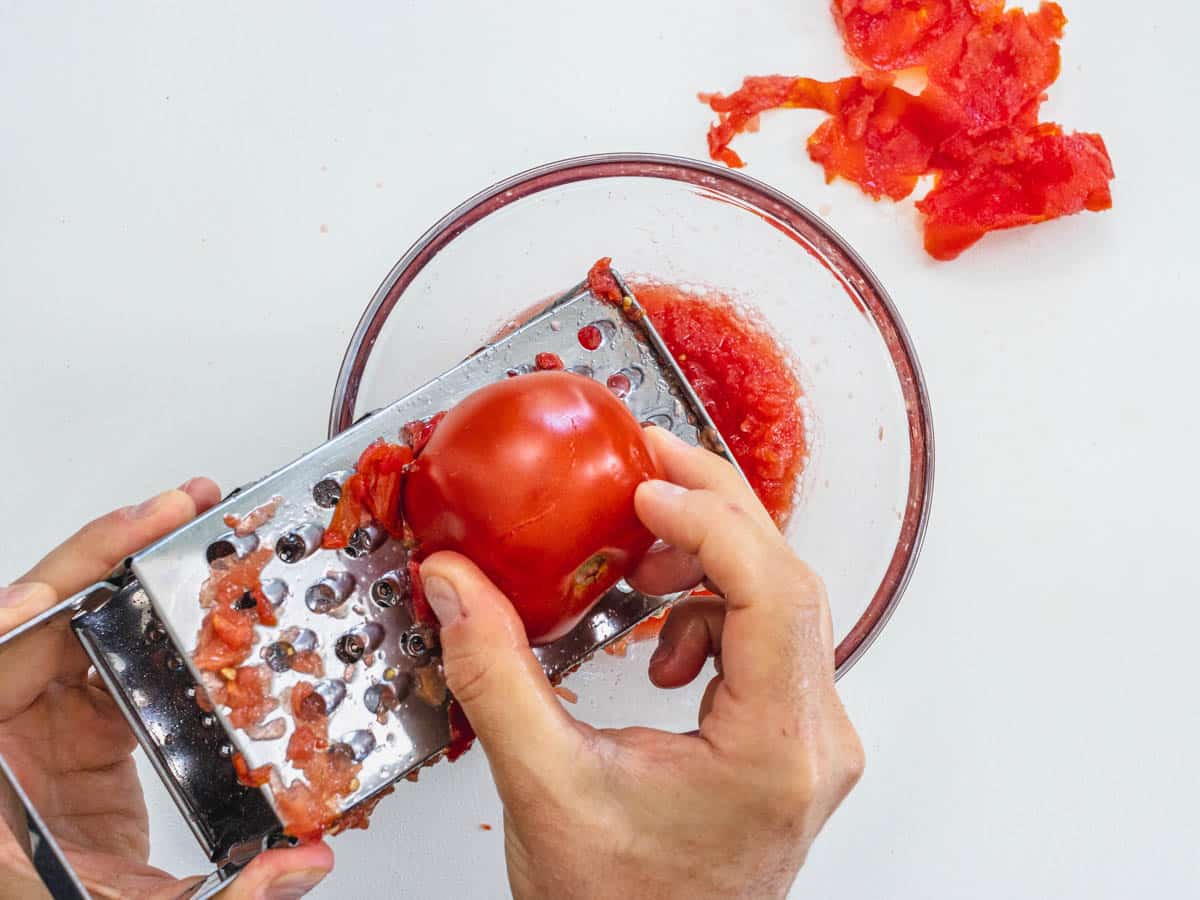 Hands with grater and tomatoes