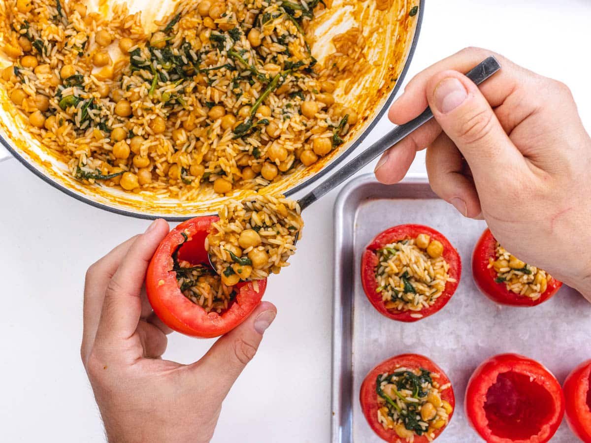 stuffing tomatoes with spoon and hands