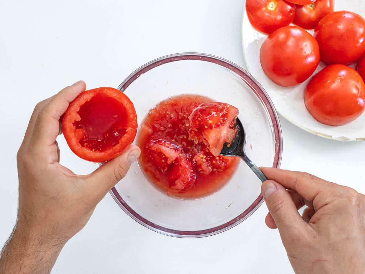 hand removes seeds from fresh tomatoes