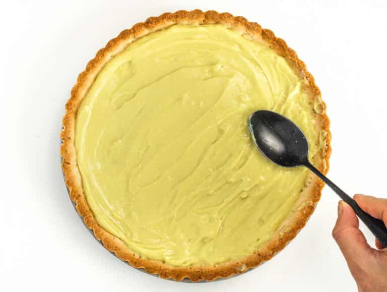 fruit tart with custard and hand with a spoon