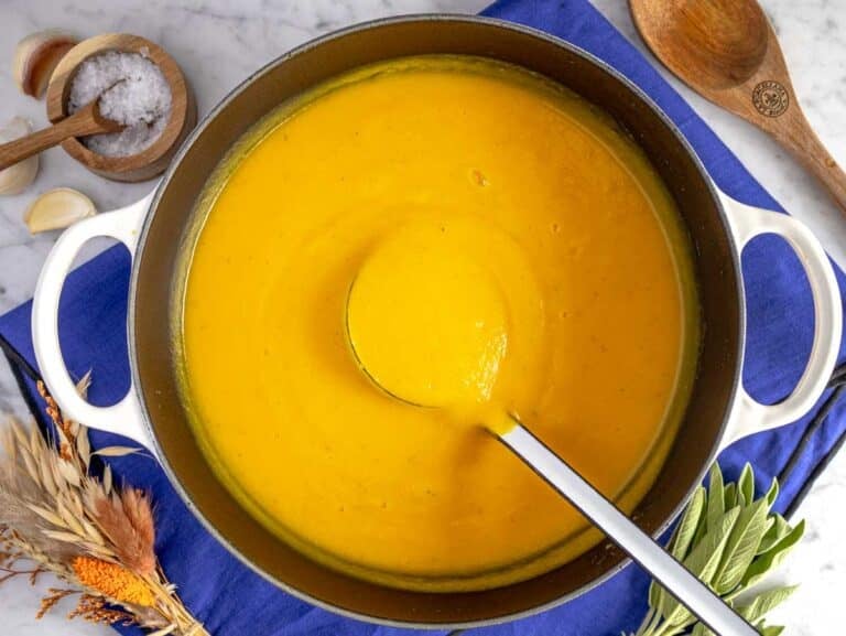 Easy butternut squash soup in a large pot with a ladle.