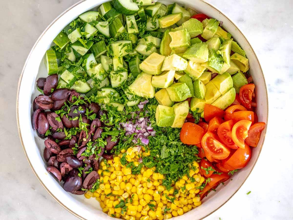 veggies, olives and avocado chopped in a white bowl