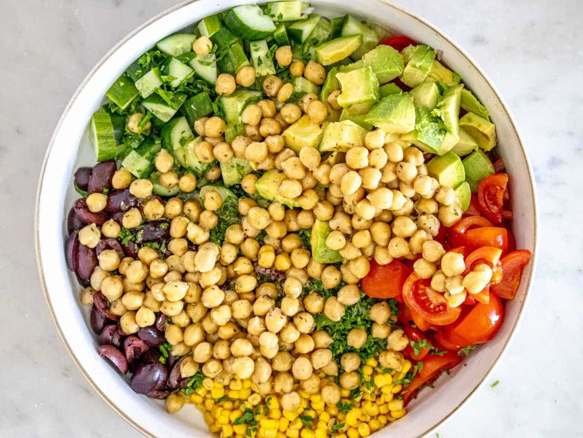 Chickpeas with veggies in a white bowl before mixing