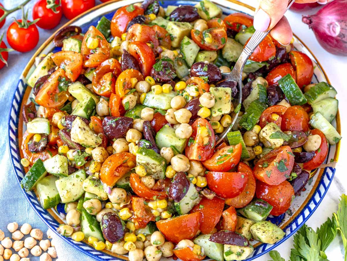 Chickpea salad recipe with cherry tomatoes on the side and a hand
