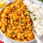 Glossy Cauliflower curry with chickpeas in creamy golden sauce topped with cilantro.