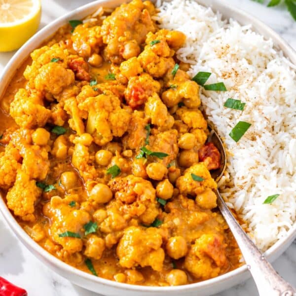 Glossy Cauliflower curry with chickpeas in creamy golden sauce topped with cilantro.