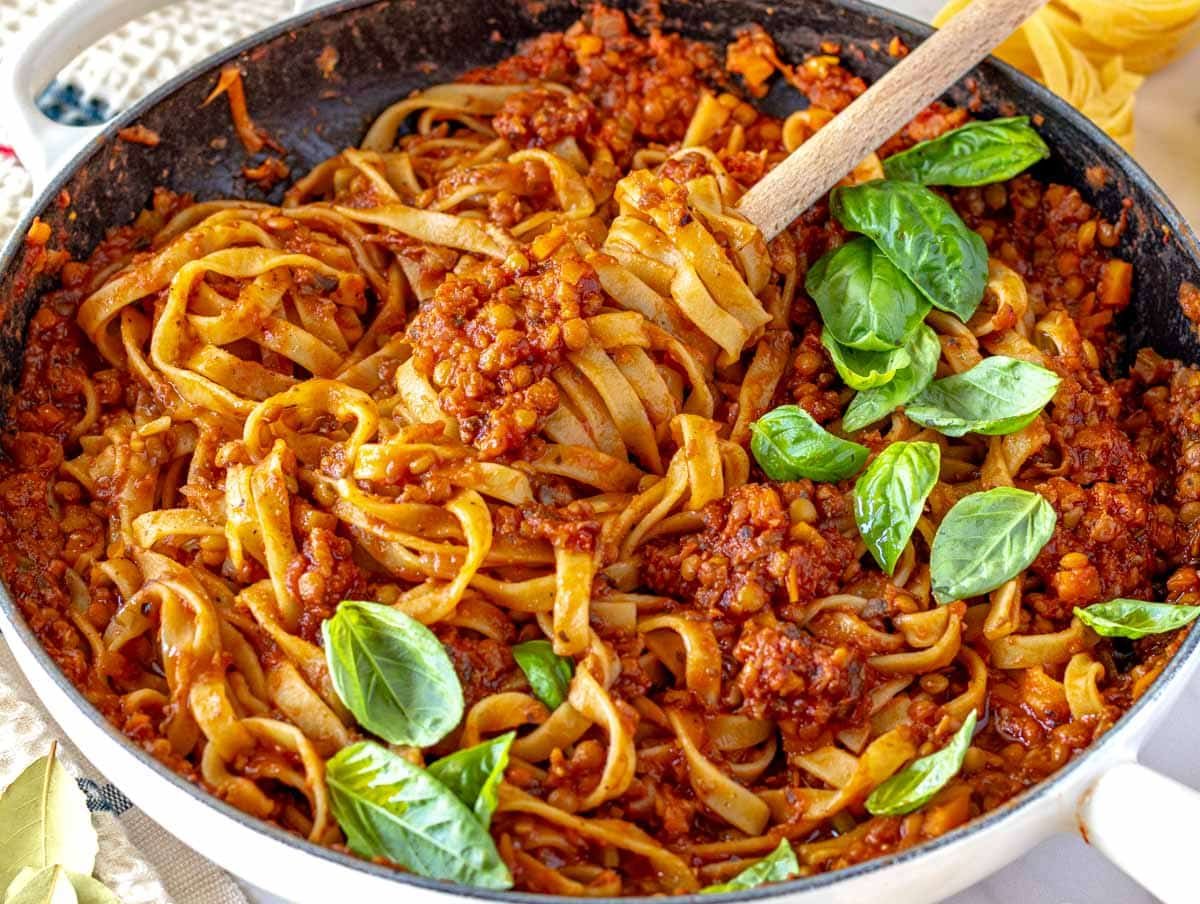 lentil bolognese with pasta in a white skillet