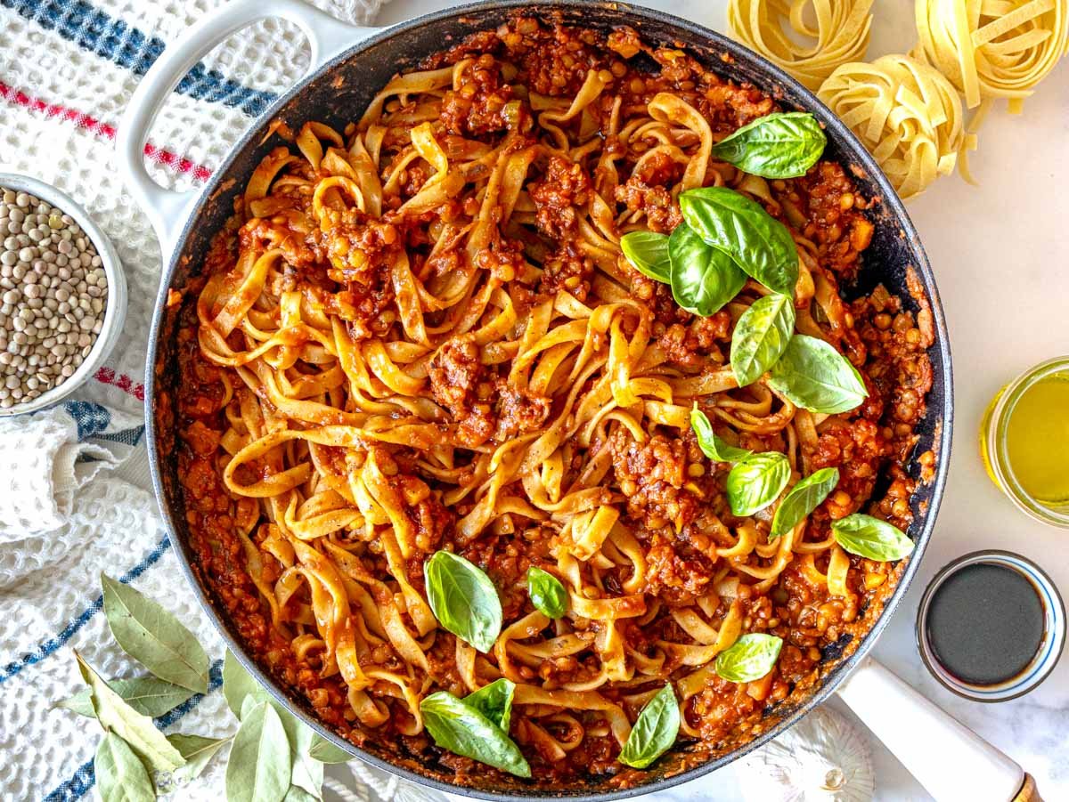 lentil bolognese with pasta in a white skillet