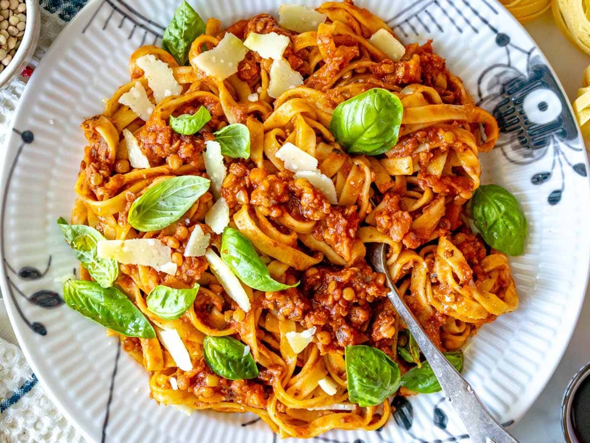 Lentil Bolognese with fresh basil, parmesan cheese and a fork