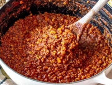 Lentil Bolognese in a Dutch oven with a wooden spoon