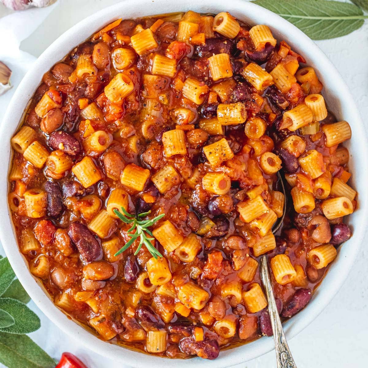 Pasta e Fagioli with a silver spoon and fresh herbs