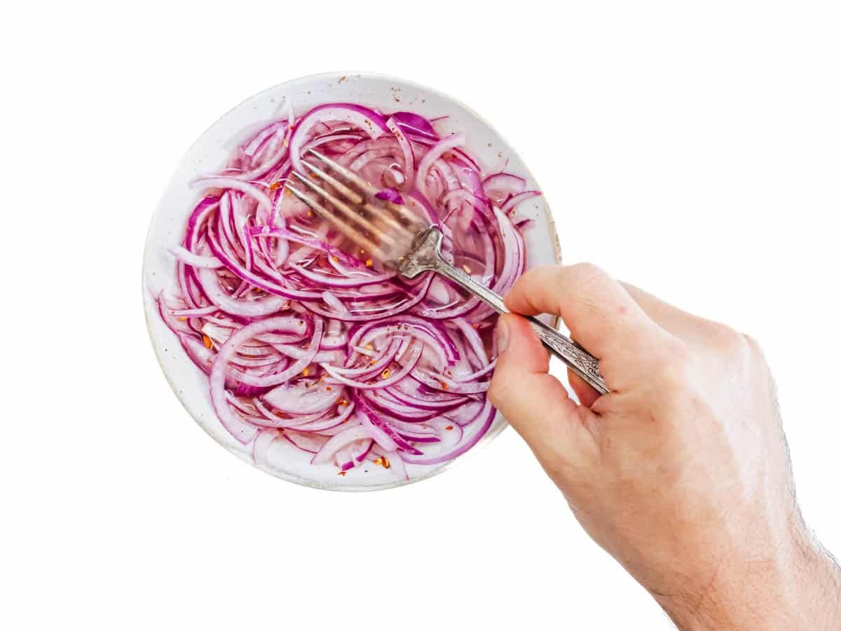 Red onions in vinegar and a hand
