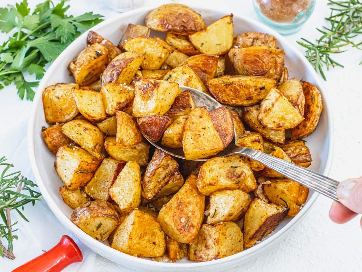 Roasted Potatoes with hand and a silver spoon