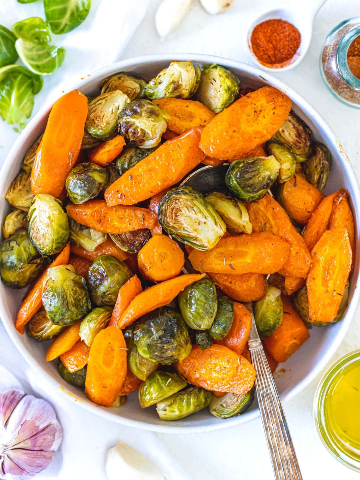 roasted carrots and Brussels sprouts in white bowl with a spoon