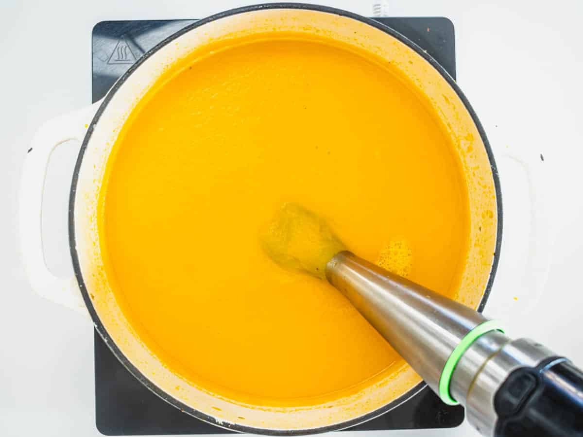 carrot soup in a casserole with a hand mixer