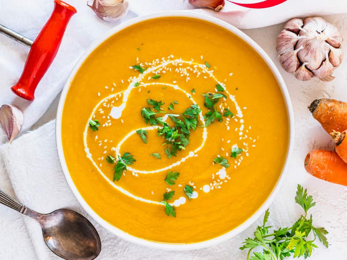 Carrot soup in a white bowl with parsley