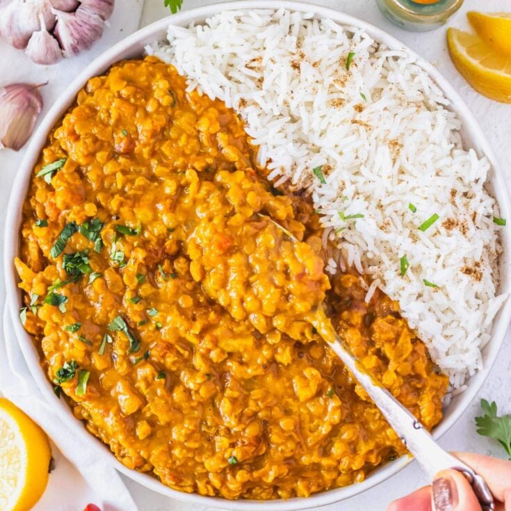 Lentil curry with white rice and a silver spoon in the curry