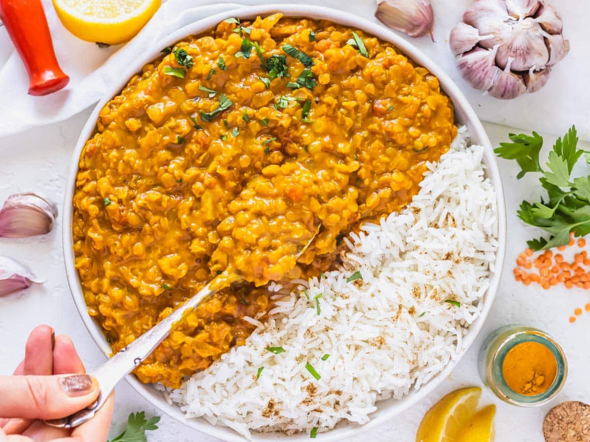 Lentil curry recipe with rice and a hand