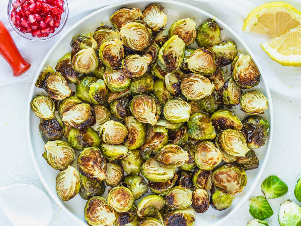 Roasted Brussels Sprouts on a plate with lemon wedges
