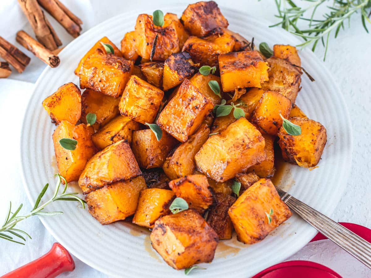 Roasted butternut squash on a plate with fresh herbs
