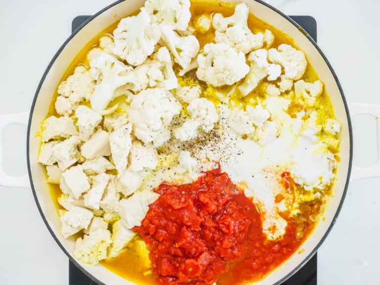 cauliflower, crushed tomato, and tofu in a skillet