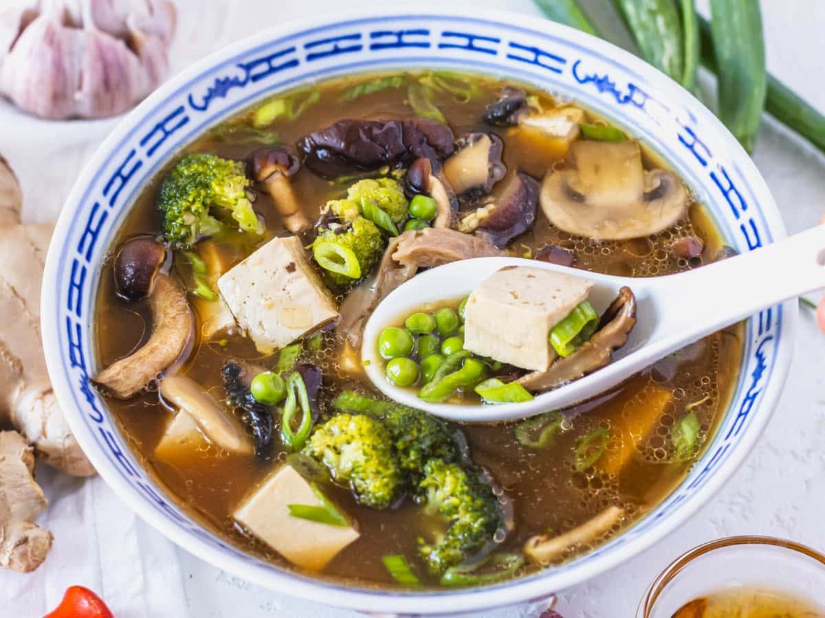 Tofu soup with peas, broccoli and a white spoon