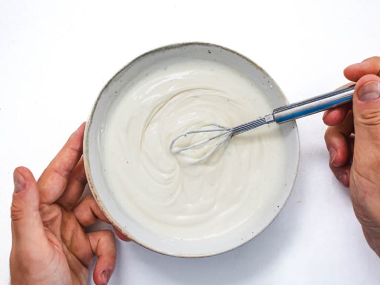 mayo yogurt dressing with hands and a whisk